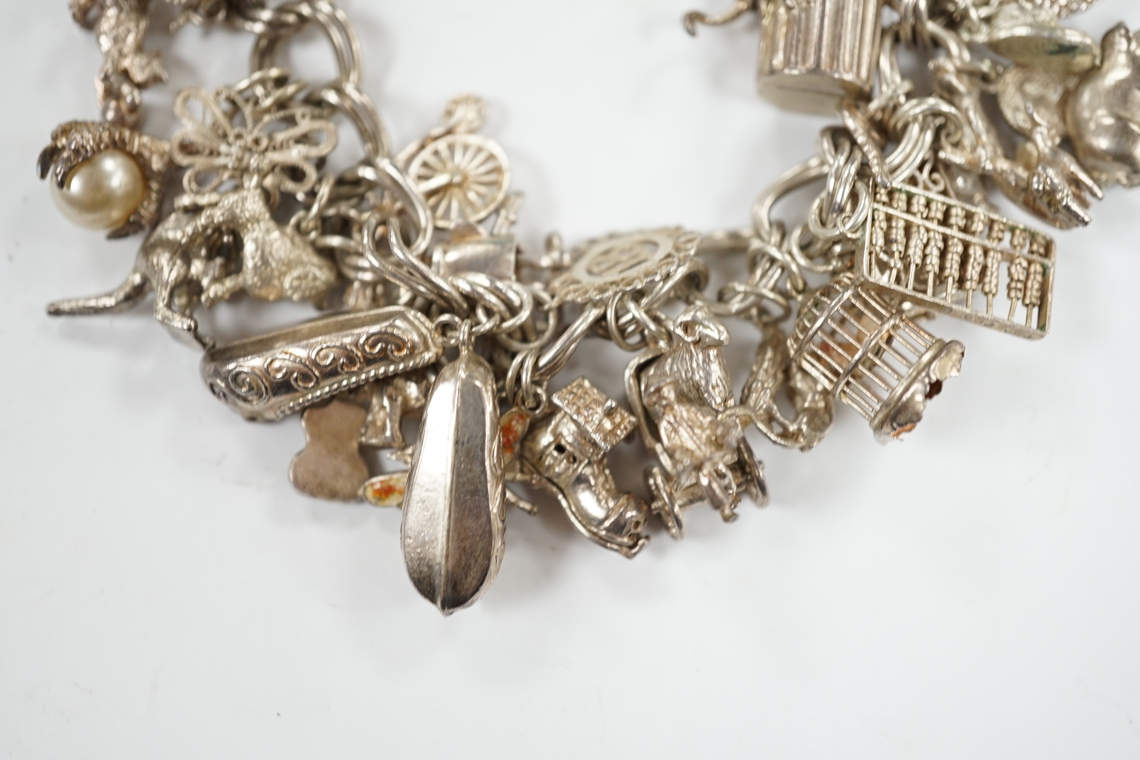 A 1970's silver charm bracelet, hung with assorted charms including birdcage, abacus, piglet, etc. and another silver charm bracelet with loose charms.